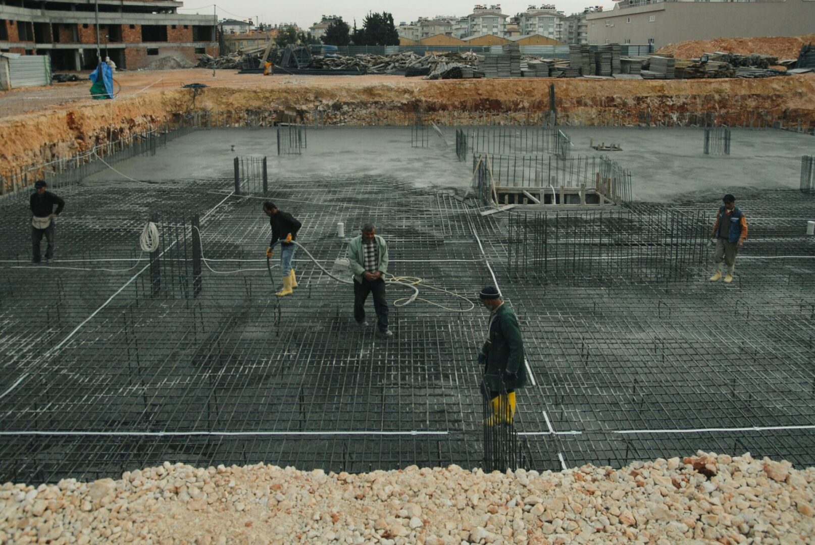 A group of men working on concrete in the dirt.